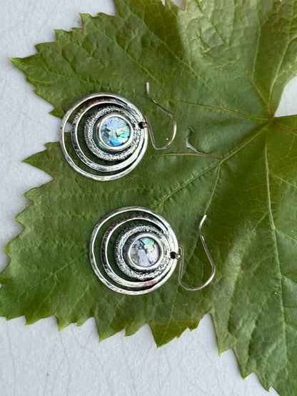 Round 3 Circles Ancient Roman Glass Sterling Earrings featuring concentric textured silver circles with iridescent ancient Roman glass centers on a green leaf background.